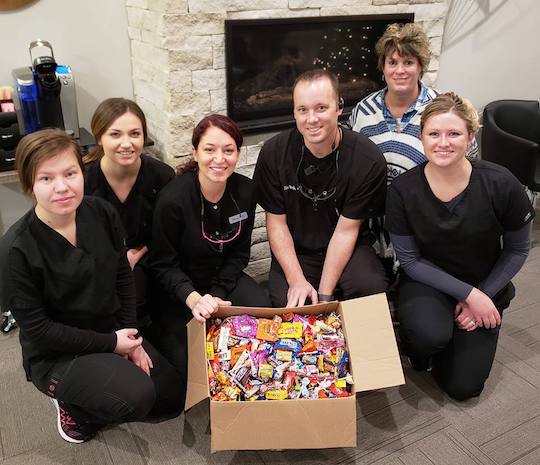 Dental team smiling with cardboard box filled with candy