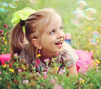 Little girl smiling in grass with bubbles