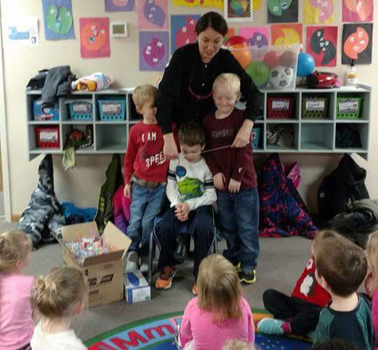 team member in classroom with three boys
