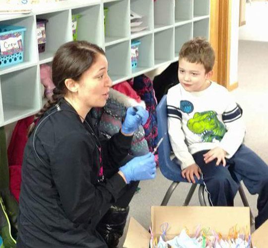 Dental team member in classroom with one boy