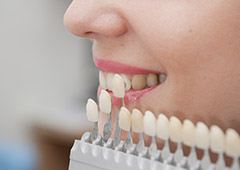 Cosmetic dentist holding dental veneer chart to a patient's smile