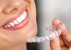 Smiling woman holding clear aligner