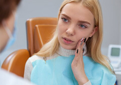 a patient touching her cheek due to tooth pain