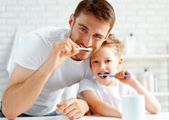 a parent and child brushing their teeth together