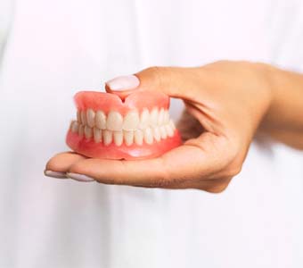 Dentist holding full dentures in Waverly
