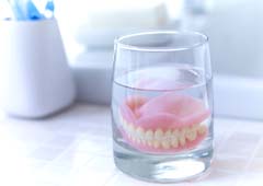 Full dentures soaking in glass of water