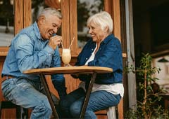 Senior man and woman sharing milkshake at restaurant table