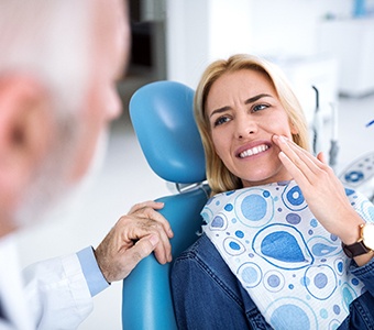 Woman holding her mouth in pain while visiting emergency dentist in Waverly