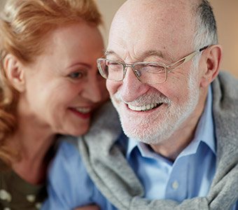 Senior man and woman smiling with implant dentures in Waverly