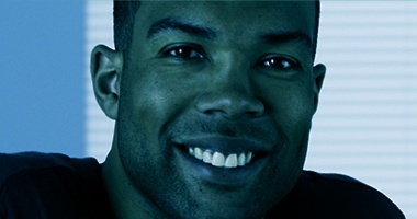 Young man smiling with window blinds in background