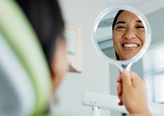 Woman smiling at reflection in dentist office