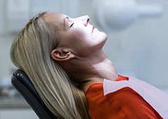 Woman leaning back in dental chair with eyes closed