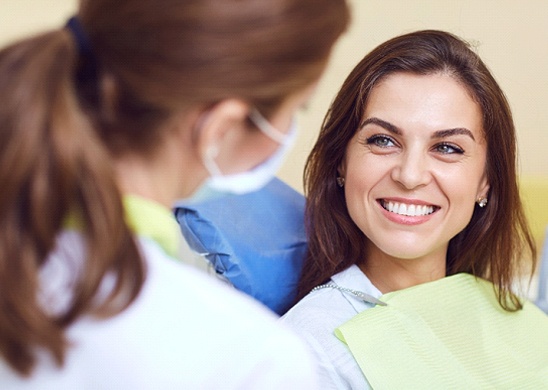 Woman sitting in dental chair and smiling at her dentist near Lincoln Nebraska