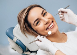 A female patient lying in dental chair and smiling as she prepares for a regular dental checkup