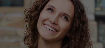 Curly haired woman smiling while looking up