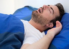 man laying in bed with mouth open