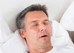 Man sleeping in white bed with mouth open
