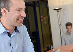 Man smiling at front desk dental team member