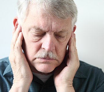 Man holding both sides of jaw in pain needing T M J treatment in Waverly