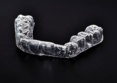 Clear occlusal splint against black background