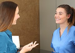 Woman talking to front desk worker at dental office