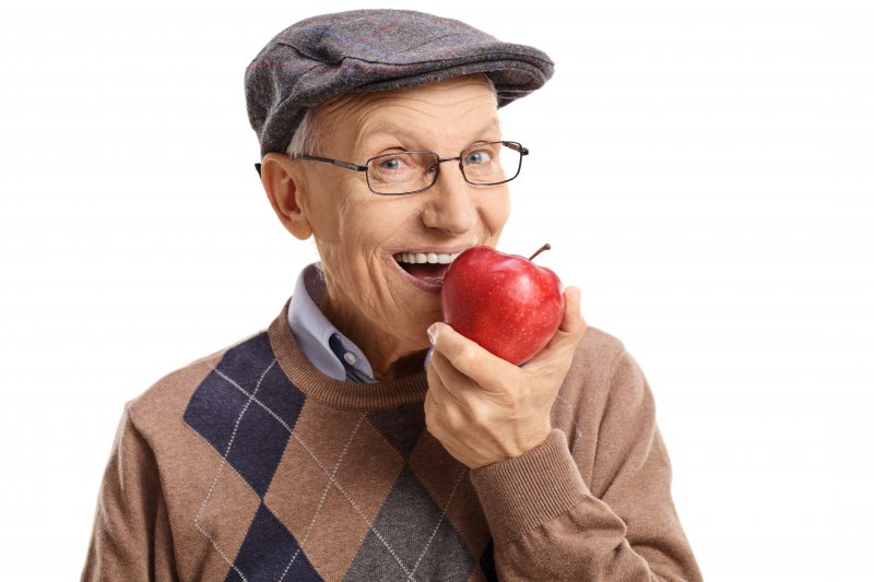 An older man biting into an apple.