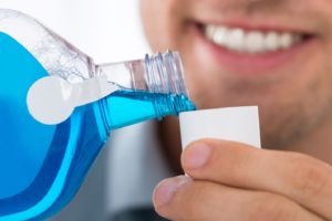 man pouring mouthwash to use before appointment with dentist