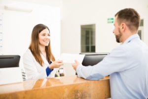 Dental receptionist helping patient with dental insurance claim