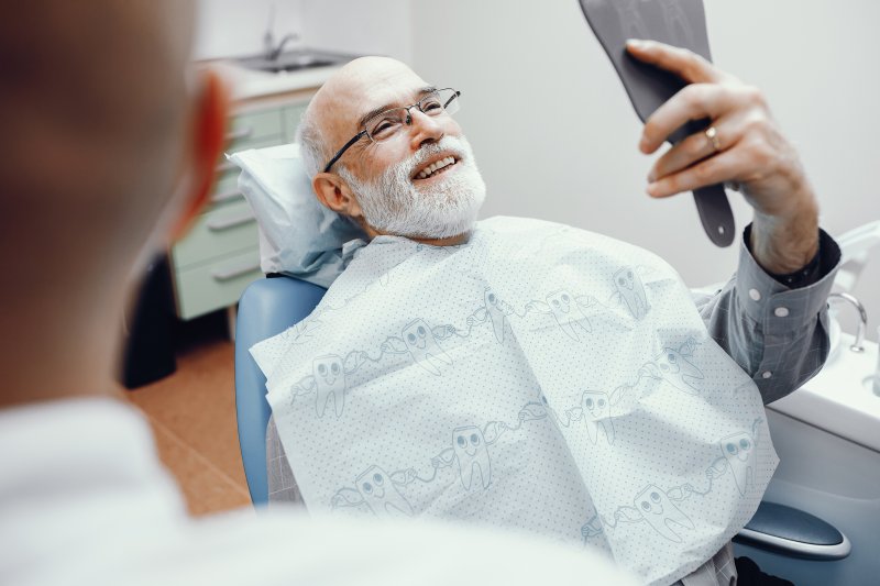 Senior gentlemen smiling at reflection during dental appointment