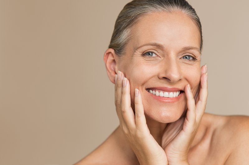 An older woman holding her face between her hands and showing off her healthy smile