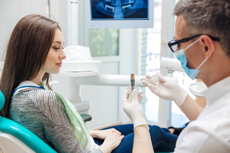 Dentist talking to patient at about dental implants