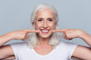 Senior woman pointing to flawless smile