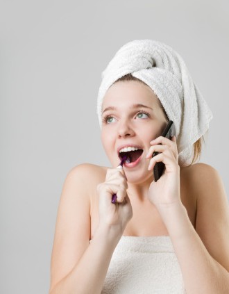 Woman brushing teeth while chatting on the phone. Visit the dentist Waverly, NE loves.