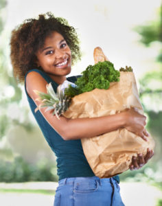 Woman with a beautiful smile and a grocery bag full of healthy foods for her teeth thanks to recommendations from the dentist waverly trusts
