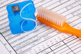 Toothbrush and floss on top of a dental insurance claim